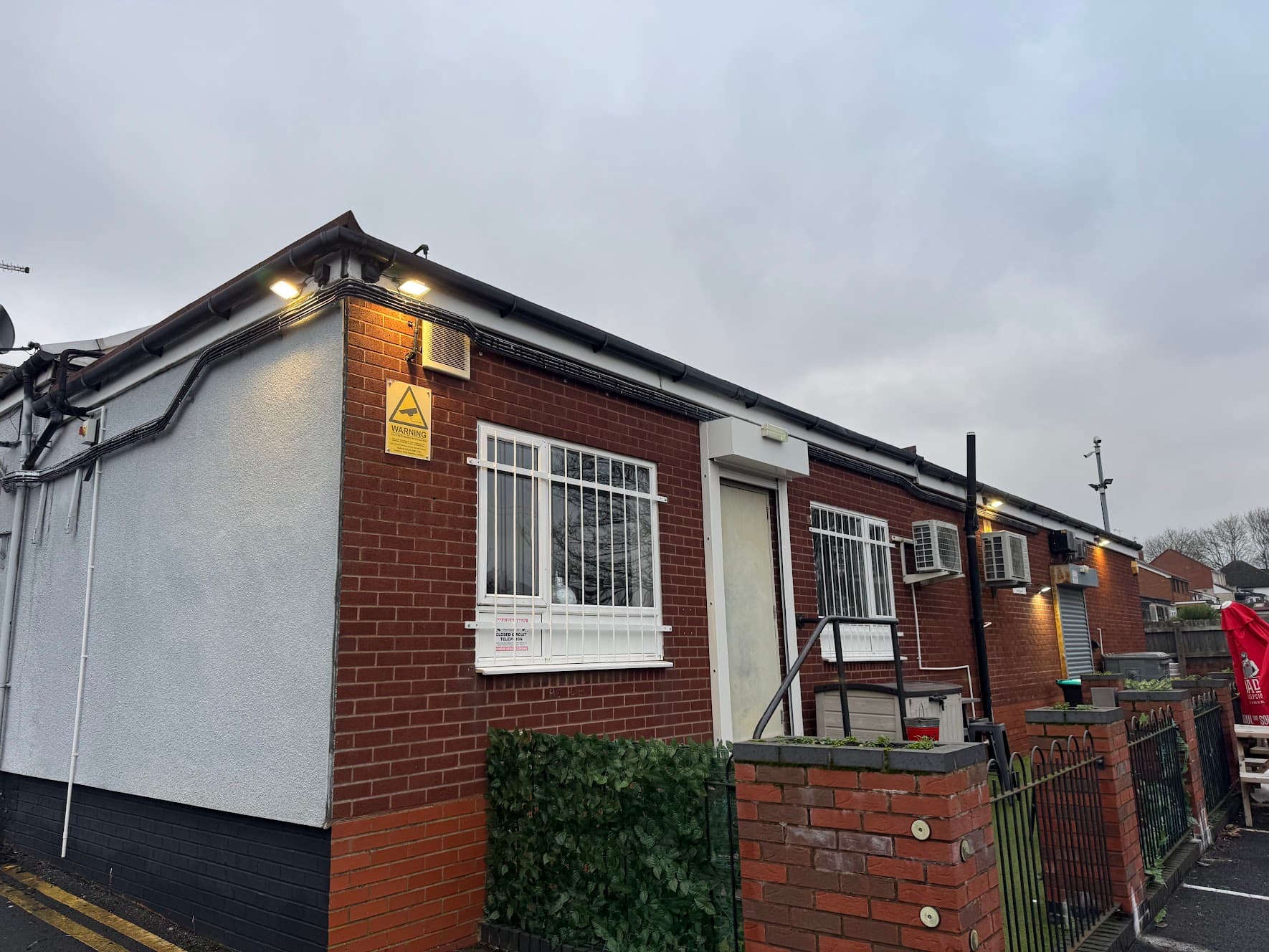 External LED lighting installed at Belt Road Working Men's Club in Hednesford, illuminating the building's eaves and entrance at dusk.