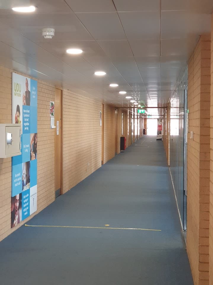 A long corridor with recessed ceiling lighting in an institutional building.