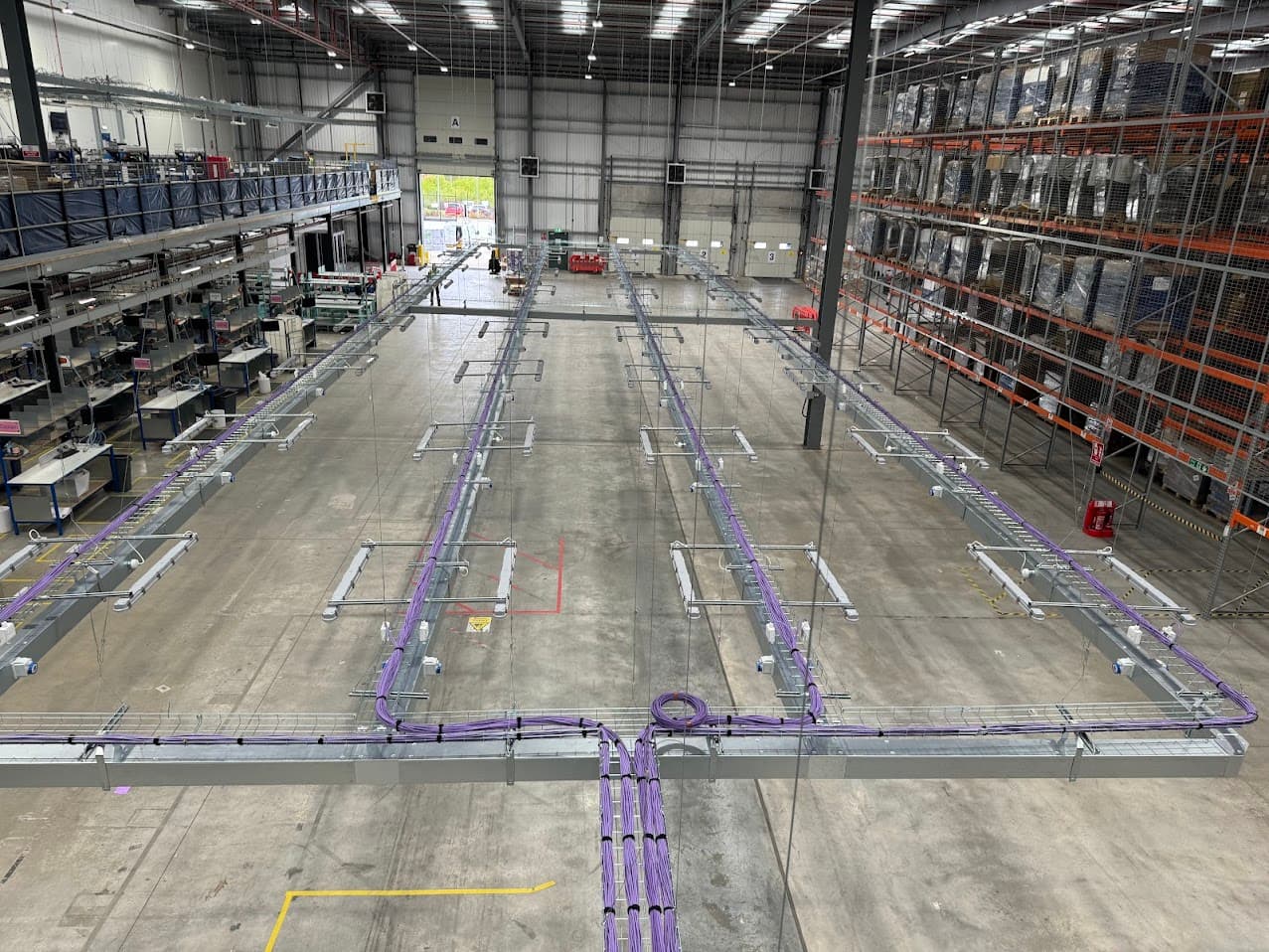 Overhead data network cabling containment installed across a large distribution warehouse during a live fit-out.